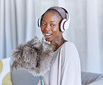 Happy, black woman and cleaning with headphones music, singing and enjoying radio while housekeeping. Smile, duster and an African girl listening to a podcast or audio to clean the living room