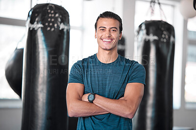 Buy stock photo Portrait, boxing and punching bag with a man in the gym, standing arms crossed for fitness or motivation. Happy, exercise and confidence with a handsome young male boxer training for a fight