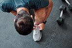 Top view, man and tie shoes in gym to start workout, training or exercise for sports. Athlete, male and tying laces on sneakers to prepare for running, cardio or exercising for health or fitness.