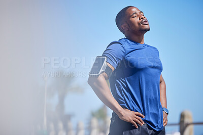 Fitness, exercise and tired man runner outdoors for break from training, cardio or running on blue sky background. Workout, stop and breathe by athletic guy outside for marathon, run or sport routine