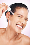 Face smile, skincare serum and woman in studio isolated on a purple background. Dermatology, cosmetics and happy mature female model apply hyaluronic acid, retinol or essential oil for anti aging.