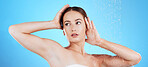 Shower, water and woman washing in studio for skincare, wellness and clean body for self care. Face of female aesthetic model, splash or drops for cleaning, hygiene and cosmetics on blue background