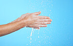 Closeup woman, water drops and washing hands on blue background, studio and color backdrop for skincare. Female model cleaning hand with liquid for showering, wellness and beauty of hygiene routine