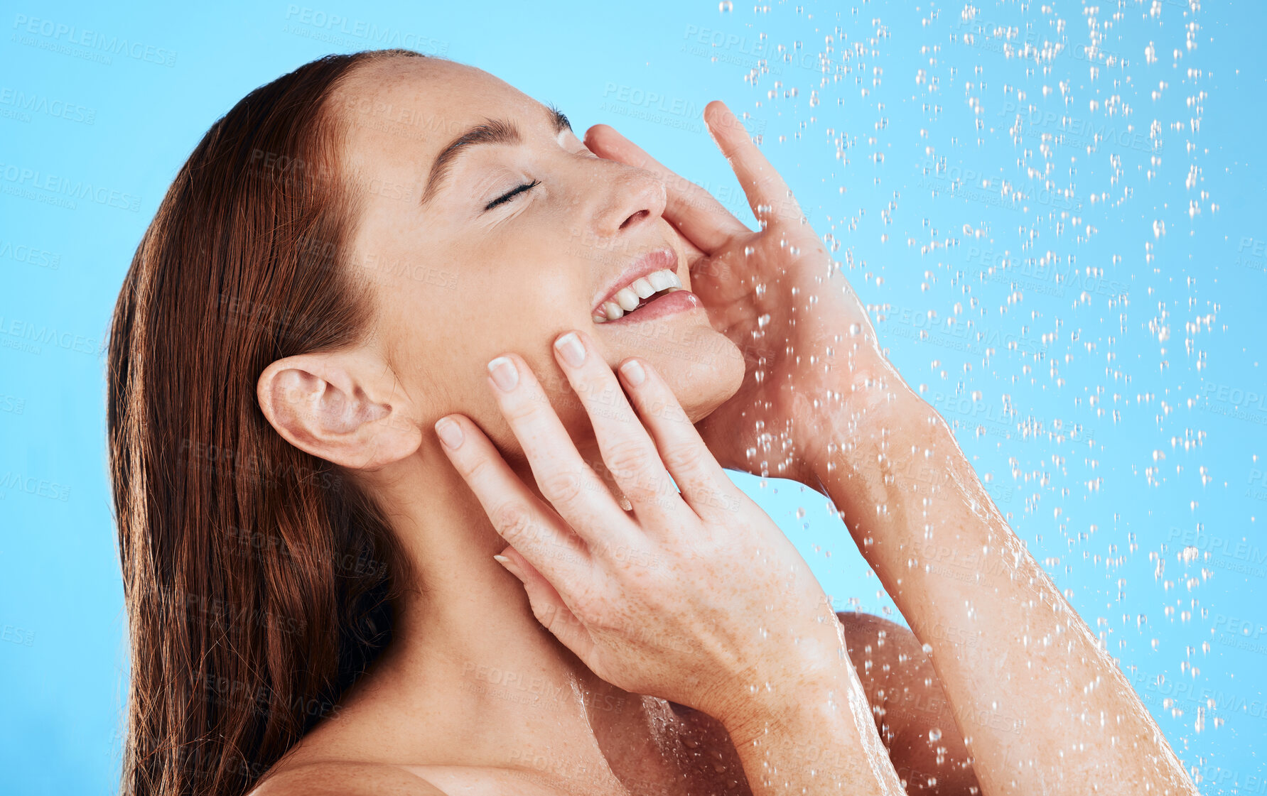 Buy stock photo Shower, water and smile of woman in studio, blue background and cleaning for hygiene. Happy female model washing with wet drops for beauty, skincare and grooming for self care, wellness and routine 