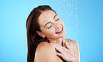 Water drop, shower and happy woman washing her body, skincare and self care isolated in a studio blue background. Aqua, beauty and female model cleaning her skin as wellness feeling calm and relaxed