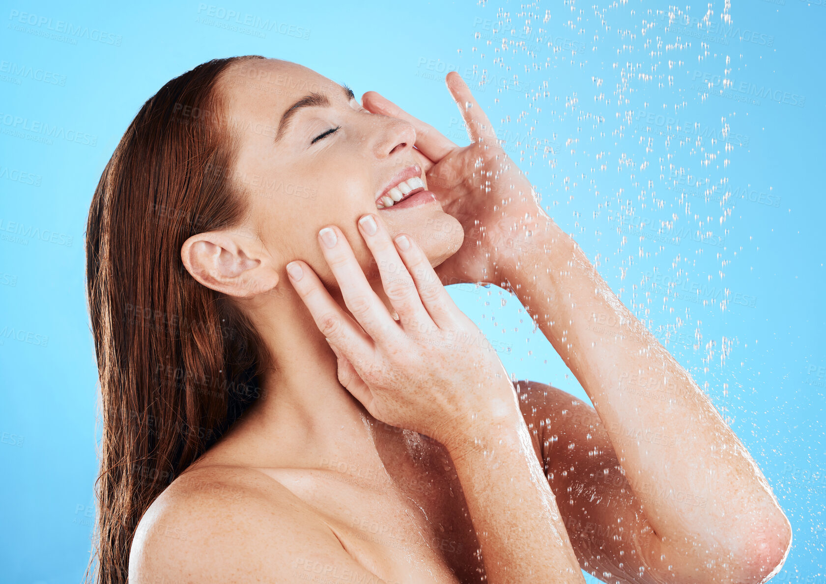 Buy stock photo Shower, water and happy woman smile in studio, blue background and cleaning for hygiene. Young female model washing with wet drops for beauty, skincare and grooming for self care, wellness or routine