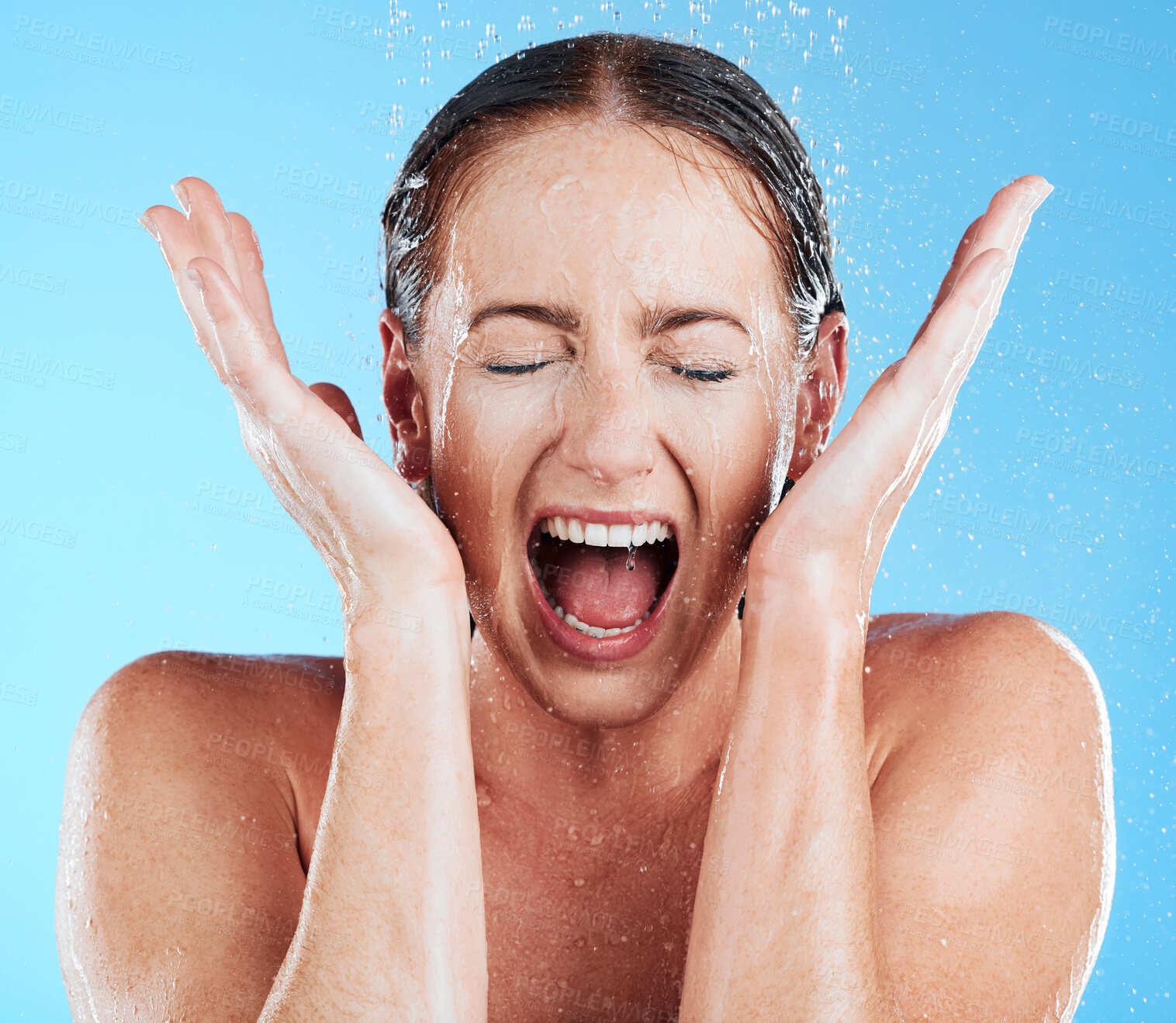 Buy stock photo Shower, water and excited woman in a studio feeling happy from cleaning and skincare. Wellness, splash and beauty routine of model screaming with facial dermatology and self care with blue background