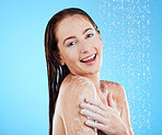 Shower, soap and woman portrait in a studio feeling happy from cleaning and skincare. Wellness, splash and beauty routine of a female model smile from dermatology and self care with blue background