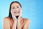 Shower, water and face of happy woman with soap in studio, blue background and skincare cleaning. Female model washing facial with foam, wet drops and beauty of self care, glow and smile on backdrop