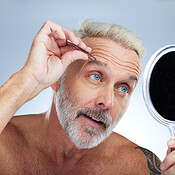 Senior man tweezers and eyebrow in studio with mirror grooming