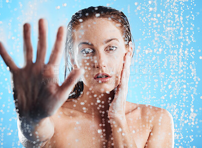 Buy stock photo Shower portrait, water drops and woman hand doing skin cleaning, wellness and beauty routine in bathroom. Isolated, blue background and studio with young female doing hair care and dermatology facial