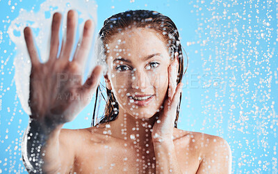 Buy stock photo Shower portrait, water drops and woman hand against glass doing skin cleaning and beauty routine. Isolated, blue background and studio with a young female doing hair care and dermatology facial