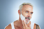 Senior man, shaving cream and smile for grooming, skincare or hair removal against a studio background. Face of mature male applying shave creme, cosmetics or product for haircare or facial treatment
