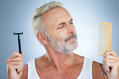 Buy stock photo Mature man, shaver and comb thinking for grooming, skincare or hair removal against studio background. thoughtful senior male holding razor blade and brush for haircare, cosmetics or facial treatment