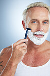 Man, face and razor with shaving cream for grooming beard, skincare or hair removal against a studio background. Mature male with shaver, creme or foam product for clean hygiene or facial treatment