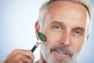 Buy stock photo Senior man, jade roller and portrait for skincare with smile, self care and wellness in studio by white background. Elderly man, facial massage and beauty with stone product, face and dermatology