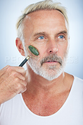 Buy stock photo Senior man, jade roller and facial skincare with clean, self care and wellness in studio by white background. Elderly model, face skin massage or beauty with stone product, glow and dermatology detox