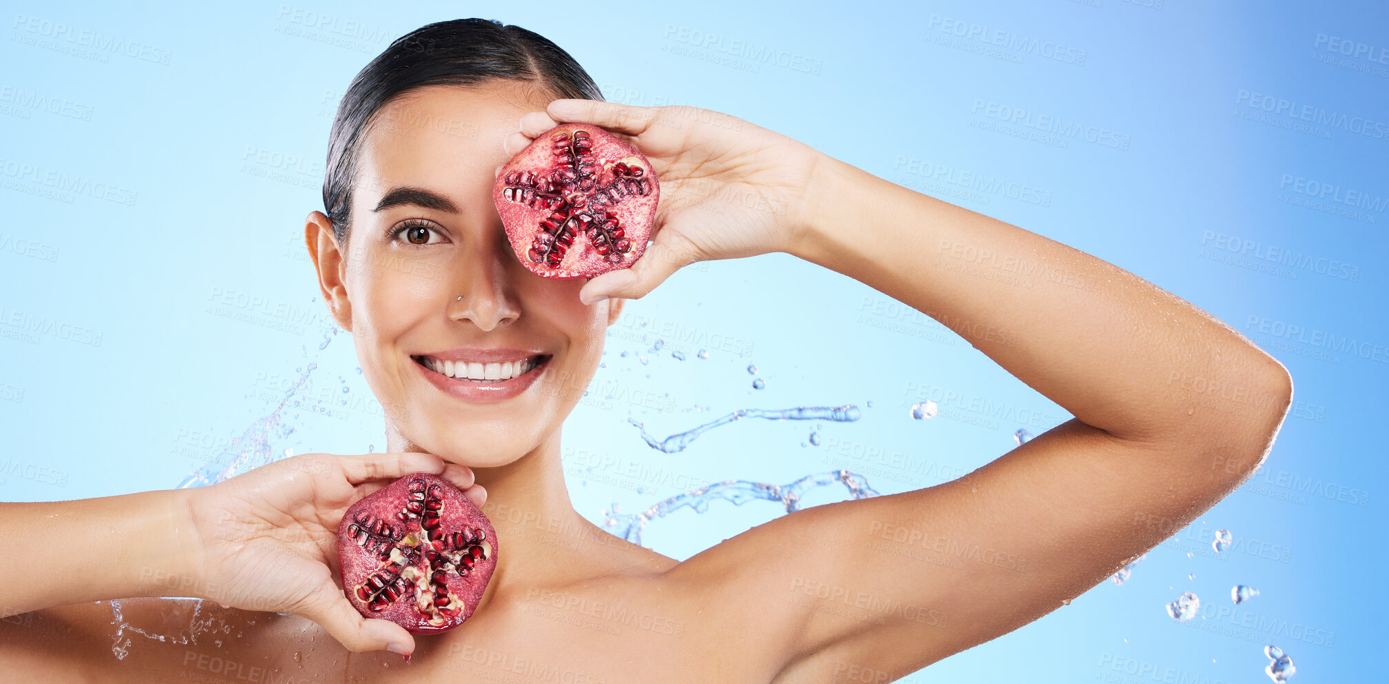 Buy stock photo Pomegranate, portrait and water splash of woman, beauty and wellness on blue background banner. Happy model, shower and healthy fruits for natural benefits, detox nutrition and skincare dermatology