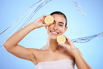 Buy stock photo Vitamin c, lemon and water splash with portrait of woman in studio for natural cosmetics, nutrition and detox. Glow, fruits and hydration with female on blue background for diet, face and skincare