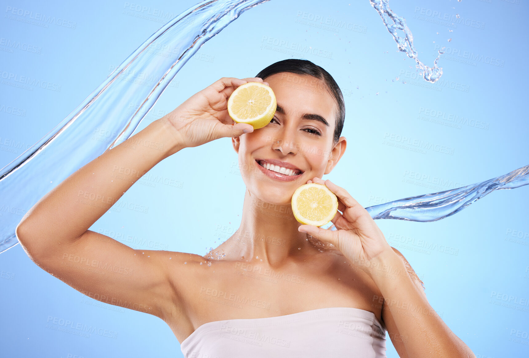 Buy stock photo Vitamin c, lemon and water splash with portrait of woman in studio for natural cosmetics, nutrition and detox. Glow, fruits and hydration with female on blue background for diet, face and skincare