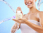 Woman, hands and water splash for skincare serum, product or cream against a blue studio background. Hand of happy female smile holding moisturizer creme for beauty cosmetics or facial treatment