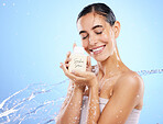 Happy woman, water splash and face with skincare serum, product or cream against blue studio background. Calm female smile holding moisturizer creme for beauty cosmetics or facial treatment on mockup