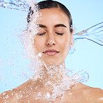 Water splash, face and skincare with a woman in studio on a blue background for hygiene or hydration. Relax, beauty and cleaning with an attractive young female in the shower for self care