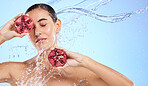 Pomegranate, face and water splash of woman, beauty and wellness on studio blue background. Calm model, shower and healthy fruits for natural benefits, detox vegan nutrition and skincare dermatology