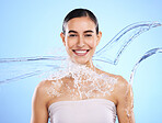 Water splash, portrait and woman shower in studio, blue background and healthy beauty of wellness skincare. Happy female model, wet and cleaning for hygiene, hydration and smile on color backdrop 