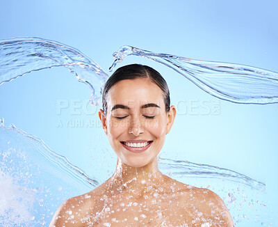 Buy stock photo Water splash, smile and woman cleaning in studio, blue background and healthy beauty of wellness skincare. Happy female model, wet and shower for hygiene, facial hydration and face on color backdrop 