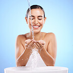 Woman, water splash and smile for skincare hygiene, hand wash or facial treatment in sink against a blue studio background. Happy female smiling in natural beauty cleanse, minerals or self care 