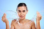 Water splash, portrait or woman with face wash for skincare, fresh body hygiene on blue background in studio. Girl model with clean hands or wellness washing in beauty grooming for facial treatment 