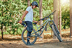 Bike, fitness and man in forest, stretching and workout for balance, cardio and energy for wellness. Male biker, guy and athlete stretch legs, nature and outdoor for exercise, cycling and warm up