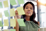 Focused woman planning or writing on glass for project management, workflow and business schedule. African person brainstorming, thinking of ideas and sticky note strategy, solution and job priority