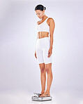 Weightloss, diet and woman weighing on a scale for health, wellness or fitness isolated in a studio white background. BMI, athlete and female measure or checking body mass after exercise or workout