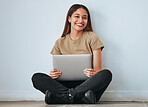 Portrait, smile and student woman with laptop in home for studying, learning or education. Technology, computer and happy female sitting on floor with pc for research on wall background for mockup.