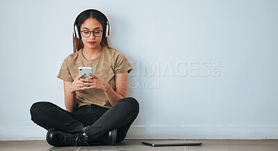 Buy stock photo Music headphones, floor and woman with phone in home by wall background with mockup. Cellphone, social media and female sitting on ground while streaming or listening to podcast, radio sound or audio