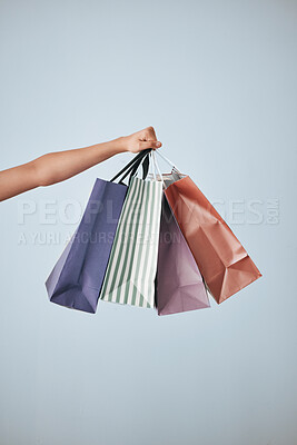 Buy stock photo Hands, shopping bags and purchase in studio sale, discount or fashion against a gray background. Hand of shopper holding bag of buying gifts, present or luxury retail products or items on copy space