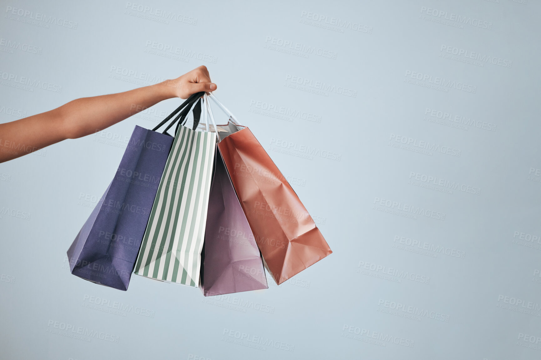 Buy stock photo Hands, shopping bags and purchase on studio mockup for fashion, discount or sale against a gray background. Hand of shopper holding bag of gifts, present or luxury retail products on copy space
