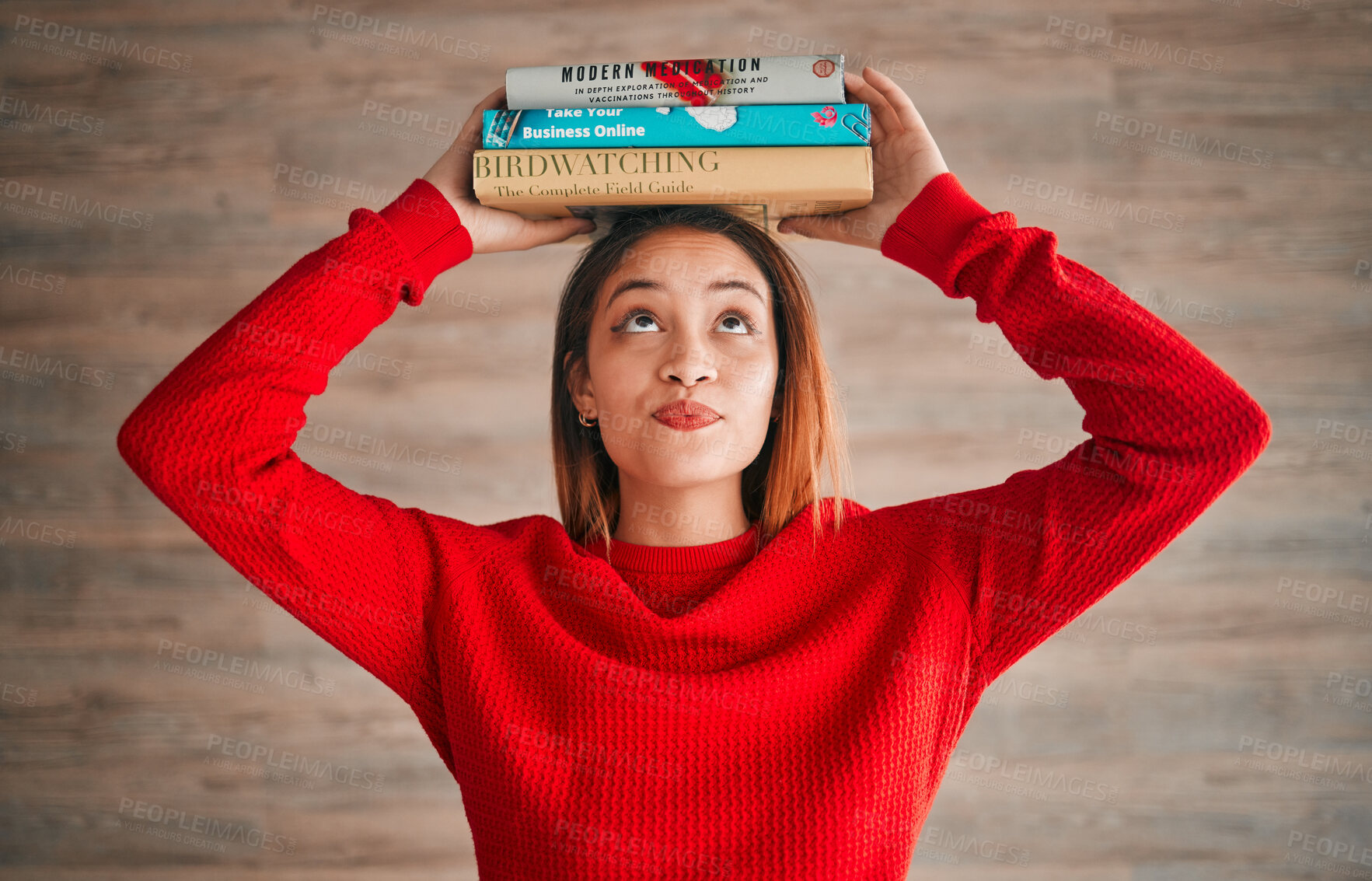 Buy stock photo Reading, student and woman with books on her head while studying in college for a test or exam. Thinking, thoughtful and young female with stories, novels or fiction standing by a wall in the library