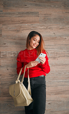 Buy stock photo Phone, fashion and a woman in studio on a wooden background typing a text message or reply. Mobile, contact and attractive young female browsing social media while carrying a handbag in red clothes