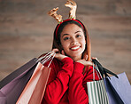 Shopping bags, portrait and woman with a christmas headband for a festive or holiday celebration. Happy, smile and face of a female model with gifts or presents with xmas reindeer ears for an event.