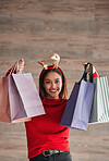 Shopping bags, happy and female with a christmas headband for a festive or holiday celebration. Happy, smile and portrait of a female model with gifts or presents with xmas reindeer ears for an event