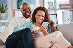 Couple, phone and laughing on sofa in home living room, social media comedy and having fun. Interracial, cellphone and funny black man and mature woman relax browsing online for comic joke or meme.