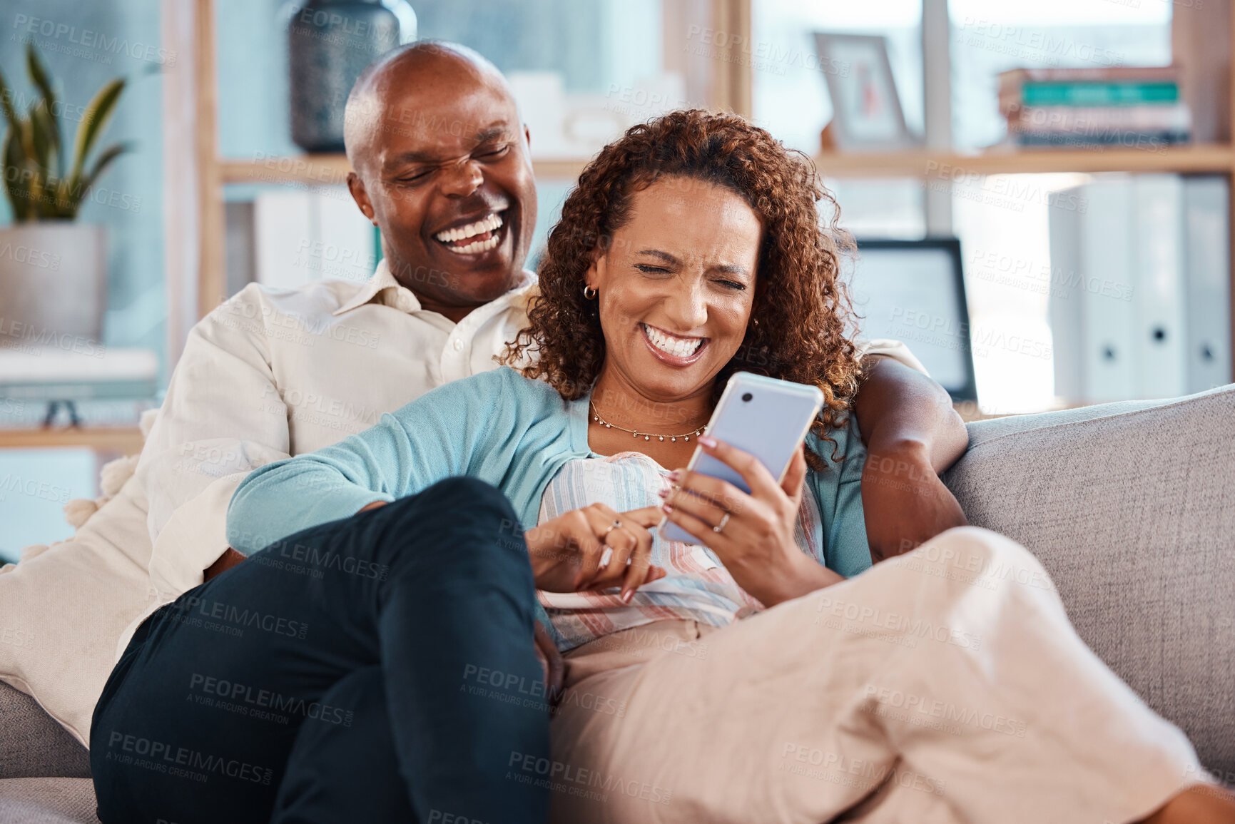 Buy stock photo Couple, phone and laughing on sofa in home living room, social media comedy and having fun. Interracial, cellphone and funny black man and mature woman relax browsing online for comic joke or meme.