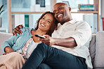 Couple, watching tv and smile on sofa in home living room, bonding and cuddle. Interracial, television and happiness of black man and mature woman relaxing while streaming movie, film or video online