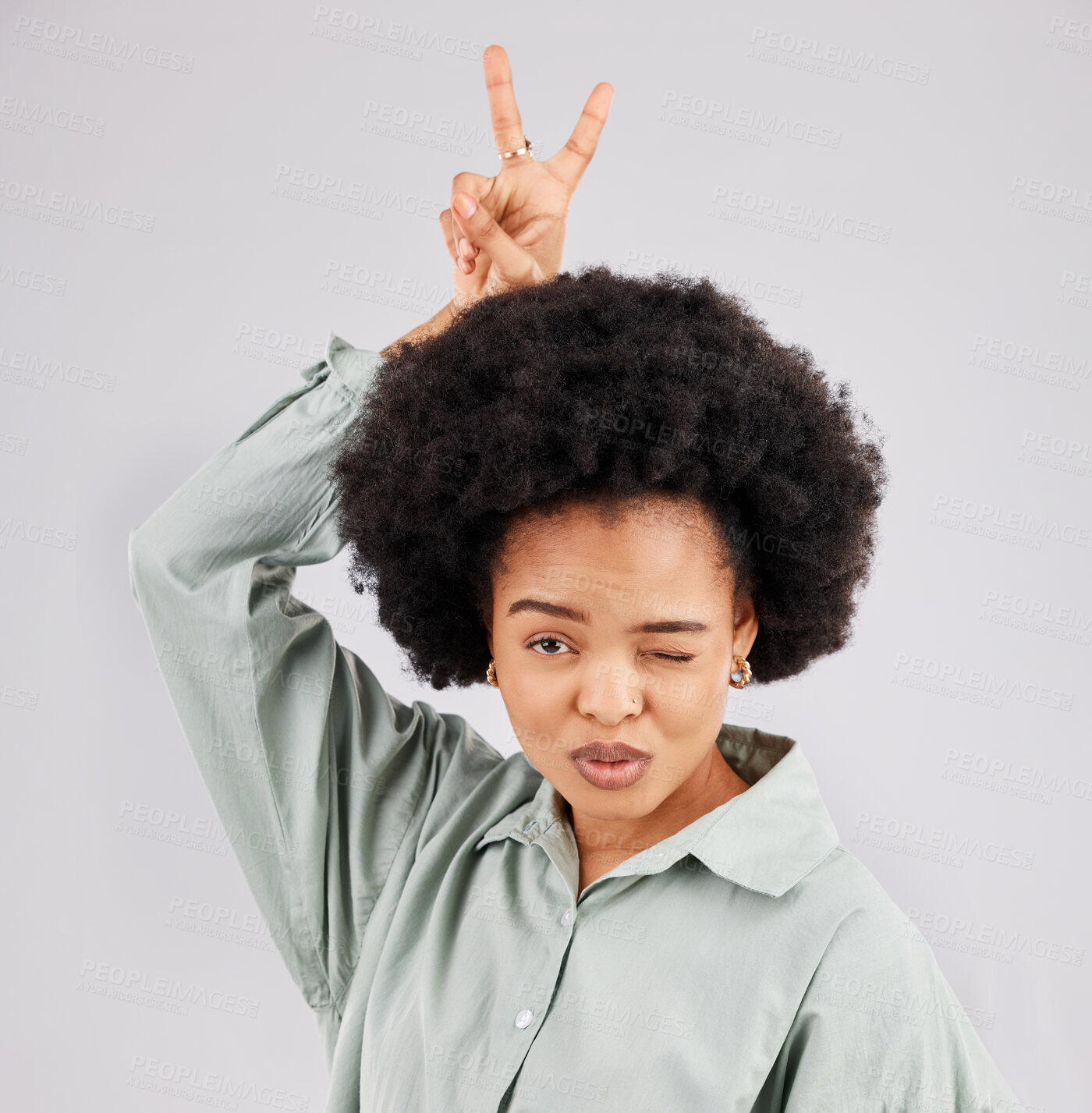 Buy stock photo Goofy, happy woman and portrait with a wink, pout and bunny ears hand sign in a studio. Isolated, grey background and peace emoji hands of a female model feeling funny with fun comedy and joke