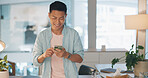 Cellphone, networking and Asian man on social media in the office typing on a lunch break. Technology, happy and male employee with a smile browsing internet or mobile app with cellphone in workplace