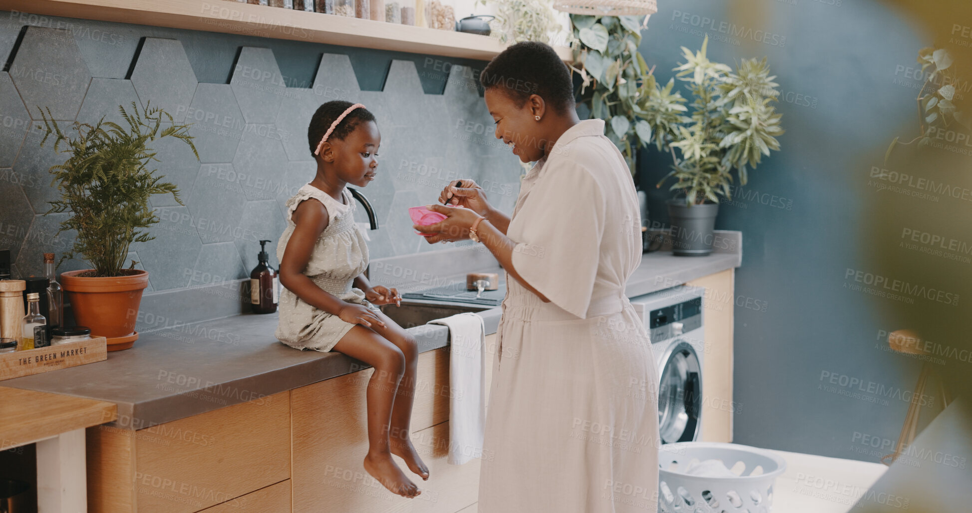 Buy stock photo Family, breakfast and a black mother feeding her daughter in the kitchen of their home while together in the morning. Kids, food or care and a little girl child with her woman parent in a house