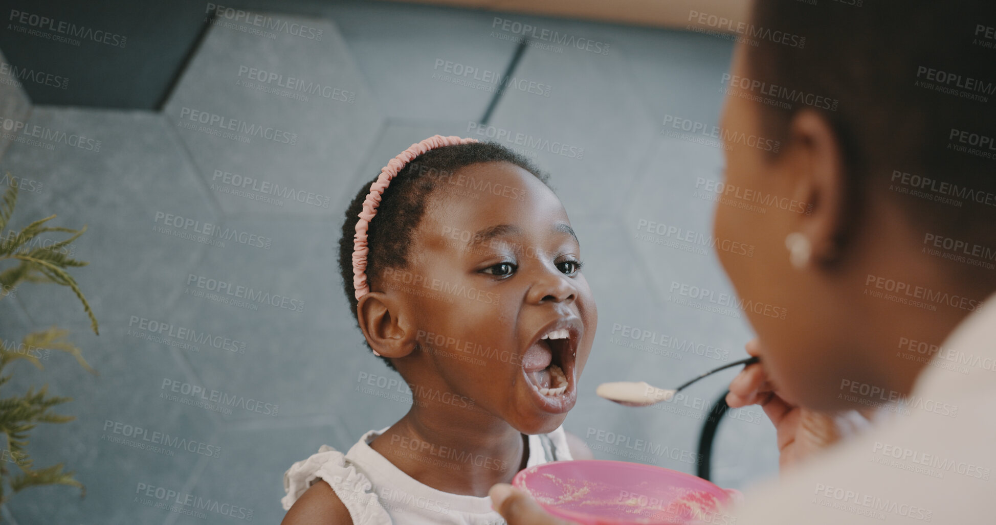 Buy stock photo Black family, breakfast and a mother feeding her daughter in the kitchen of their home while together in the morning. Children, food or care and a little girl child with her woman parent in a house